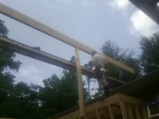 Carpenter setting a ridge beam over a new addition frame — Ice Dam Removal by Roofing Brothers in Winton