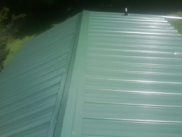 New green metal panels meeting at the ridge of a roof — Flat Roof Repair work by our crew in Winton