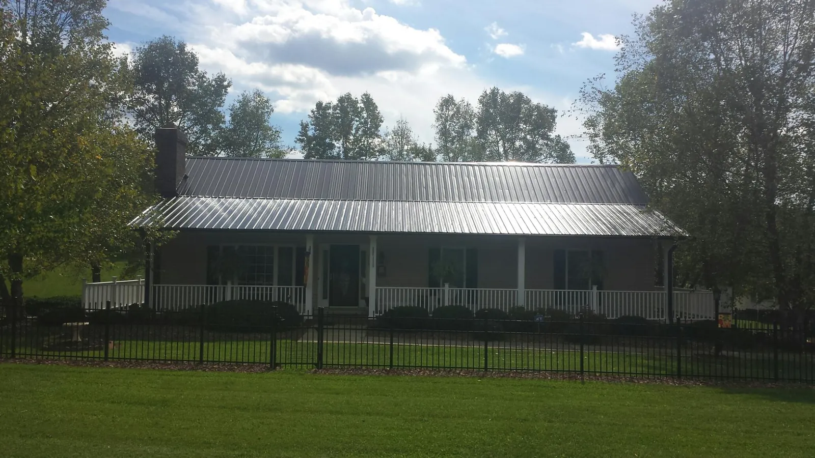Gray metal roof on a brick ranch with a full width front porch — Gutter Guard Installation work by our crew in Winton