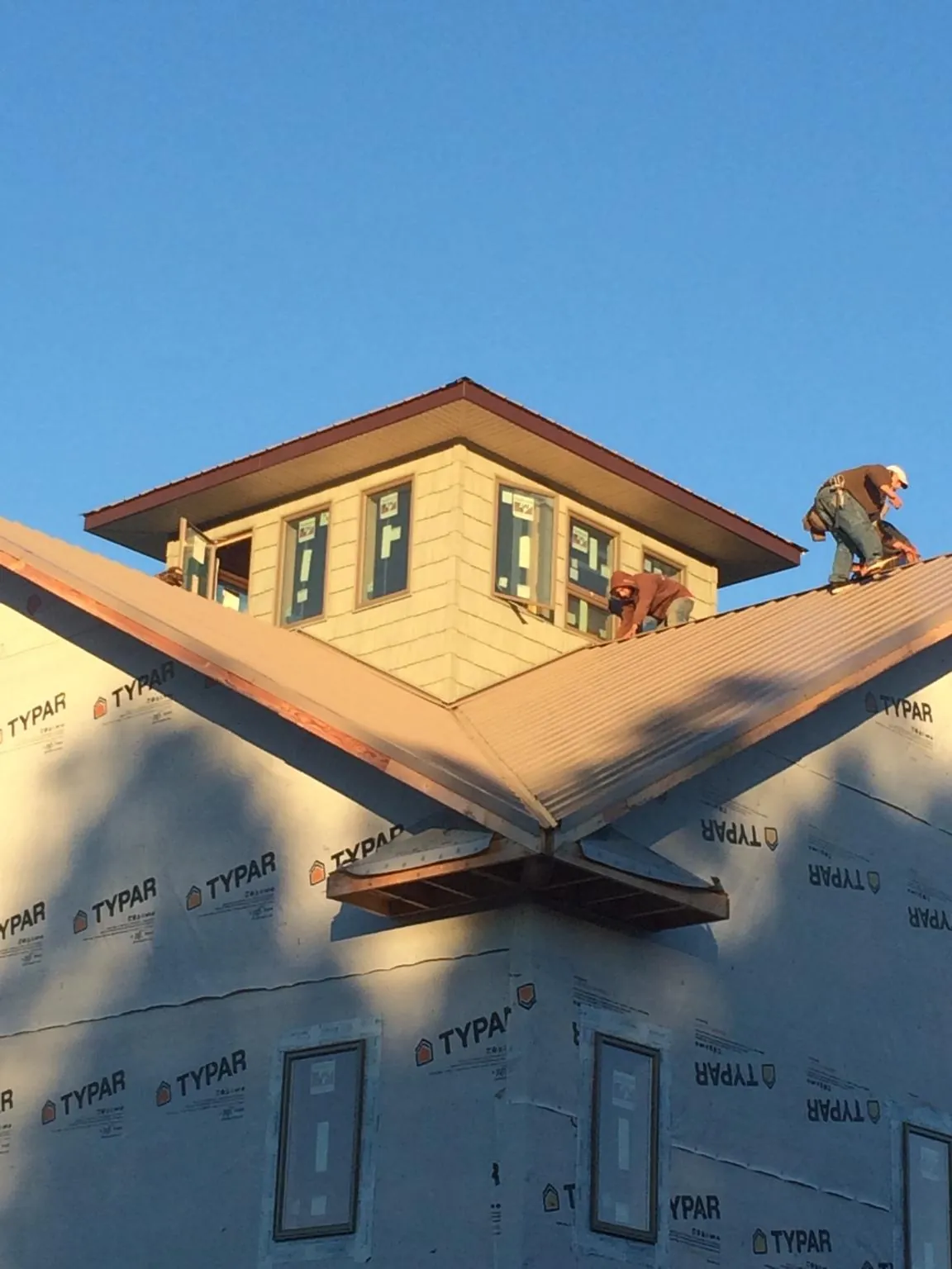 Roofers working around a rooftop cupola on a new metal roof at sunset — Roof Waterproofing in Winton by Roofing Brothers